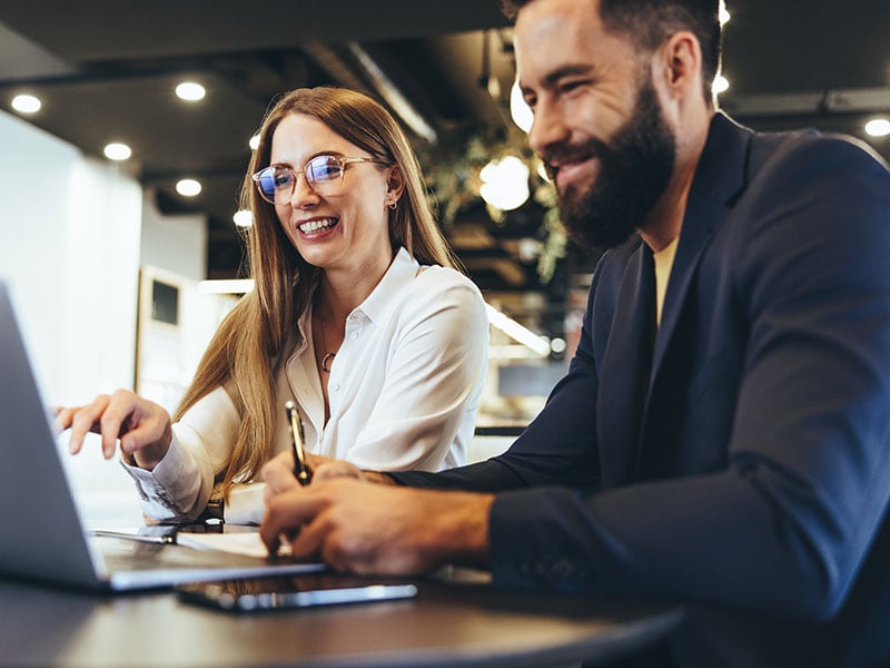 Cheerful businesspeople using a laptop in an office