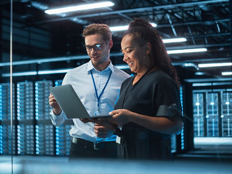 Senior-CEO-Talking-to-Young-Confident-Manager-while-Using-Computer-in-Modern-Office